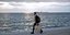 Ενας νέος άνδρας περπατά φορώντας μάσκα στην παραλία Θεσσαλονίκης
