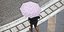 Μια γυναίκα περπατά με ομπρέλα στη βροχή