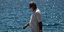 Ενας άνδρας με μάσκα περπατά σε λιακάδα στην παραλία του Φλοίσβου