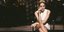Η Σάρον Στόουν κάθεται σταυροπόδι με λευκό φόρεμα