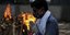 άνδρας με μάσκα και χέρια στο στήθος κοντά σε φωτιά στην Ινδία