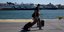 Ενας ταξιδιώτης στο λιμάνι του Πειραιά προχωρά με τις βαλίτσες του