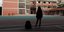 Μαθήτρια σχολείου στη σκιά του προαύλιου όρθια με την τσάντα της δίπλα στα πόδια της