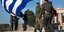 Ο Μαργαρίτης Σχοινάς προστατεύει την ΠτΔ ενώ πέφτει πάνω της η τεράστια ελληνική σημαία