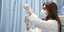 γυναίκα νοσηλεύτρια με μάσκα και λευκα γάντια κρατάει εμβόλιο