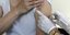 εμβόλιο σε μπράτσο από νοσηλεύτρια με λευκά γάντια και χρυσό ρολόι
