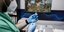 νοσηλευτής με μπλε γάντια κρατάει εμβόλιο 