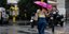 γυναίκα με ροζ ομπρέλα περπατάει στον δρόμο με βροχή