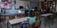 μαθητές κάθονται σε θρανία σε αίθουσα σχολείου με δασκάλα να κάνει μάθημα