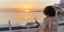 Τουρίστρια απολαμβάνει το ποτό της με θέα το ηλιοβασίλεμα