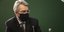 Τζέφρι Πάιατ με μάσκα σε ομιλία μπροστά από πράσινο τοίχο