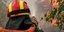 πυροσβέστης με κράνος και μάνικα ρίχνει νερό σε φωτιά στην Αττική