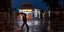 Βροχή βράδυ στην Αθήνα με φόντο φωτισμένο περίπτερο 