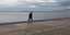 Άνδρας περπατά με την ομπρέλα του στην παραλία Θεσσαλονίκης
