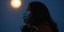 Γυναίκα με μάσκα στην Ουχάν με φόντο το φεγγάρι