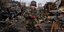 Ένας 7χρονος πιτσιρικάς Ουκρανός μπροστά από συντρίμια, κρατά ένα ξύλινο όπλο