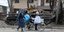 Άμαχοι στη Μαριούπολη περνούν μπροστά από ένα κατεστραμμένο τανκ