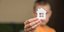 ένα παιδί κρατά ένα χάρτινο σπίτι