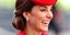 Η Κέιτ Μίντλετον χαμογελαστή με κόκκινο παλτό κόκκινο καπέλο και κότσο