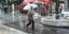 Γυναίκα περπατά με την ομπρέλα της σε κεντρικό δρόμο της Αθήνας εν μέσω κακοκαιρίας