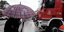 Ατομα με ομπρέλα μπροστά από όχημα της πυροσβεστικής