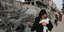 Παλαιστίνια στη λωρίδα της Γάζας με το μωρό της μπροστά από ερείπια κτιρίου από τους ισραηλινούς βομβαρδισμούς