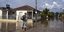 Aνδρας περπατά σε πλημμυρισμένο χωριό στη Θεσσαλία