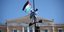 H στιγμή που νεαρός Παλαιστίνιος υψώνει τη σημαία της χώρας του μαζί με την ελληνική σε κολώνα στο Σύνταγμα