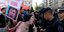 διαδηλώτρια στην αργεντινή με πανό που δείχνει το πρόσωπο του μιλέι, φωνάζει μπροστά από αστυνομικούς