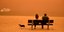 Δύο άτομα κάθονται σε παγκάκι εν μέσω αφρικανικής σκόνης