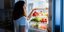 Μια γυναίκα ψάχνει στο ψυγείο να φάει