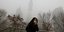 Γυναίκα προσπαθεί να προστατευθεί από την ατμοσφαιρική ρύπανση στο Πεκίνο / Φωτογραφία: ΑΡ