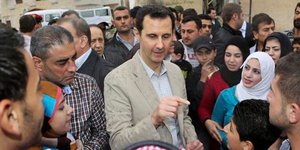 O Aσαντ στη βροχή ανάμεσα στο πλήθος. Ανακοίνωσε ότι θα είναι υποψήφιος στις προ