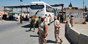Λεωφορεία με αντάρτες αναχωρούν υπό το βλέμμα στρατιωτών του Άσαντ (Φωτογραφία: AP)