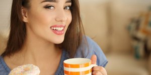 Μια γυναίκα τρώει ένα ντόνατ και πίνει νερό