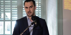 Αλέξης Χαρίτσης μιλάει μπροστά σε παράθυρο