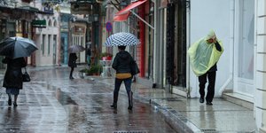 Βροχή, τρεις άνθρωποι με ομπρέλες με ομπρέλες