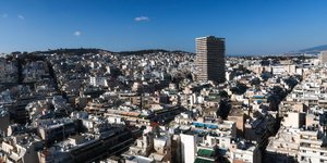 Εικόνα της Αθήνας από ψηλά με πολυκατοικίες και τον Πύργο των Αθηνών