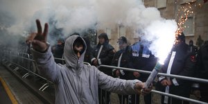 Διαδηλωτής με καπνογόνο στο χέρι έξω από το κυβερνητικό κτήριο στην Αλβανία 