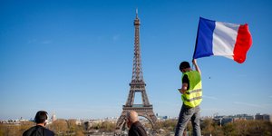 Ανδρας κρατά την σημαία της Γαλλίας μπροστά από το πύργο του Άιφελ