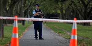 Αστυνομικός κρατά το όπλο του πίσω από πορτοκαλί κώνους