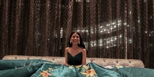 Γυναίκα κάθεται σε καναπέ φορώντας ένα πράσινο φόρεμα με λουλούδια