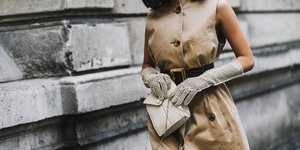 Γυναίκα με μπεζ φόρεμα και εκρού γάντια και τσάντα