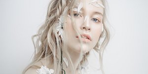 Μια γυναίκα με λευκή επιδερμίδα και λουλούδια στο πρόσωπο