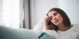 Γυναίκα κάθεται στον καναπέ και σκέφτεται