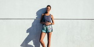 Γυναίκα χαμογελάει και φοράει αθλητικό σορτσάκι και μπλούζα