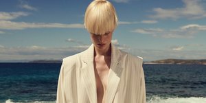 Γυναίκα σε παραλία φορά λευκό κοστούμι 