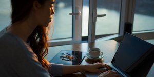 Γυναίκα κάθεται μπροστά σε υπολογιστή και δουλεύει