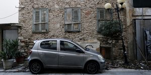 Παρκαρισμένο αυτοκίνητο μπροστά από μισογκρεμισμένο σπίτι