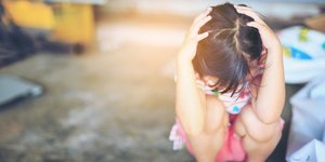 Εικόνα αρχείου από ένα κοριτσάκι να κρύβει το πρόσωπό του και να κρατά το κεφάλι του χαμηλωμένο